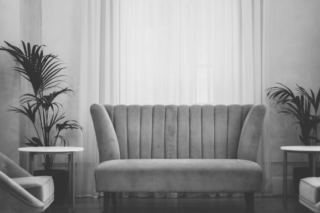 An empty seating area with a sofa, chairs, and plants.